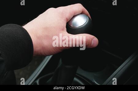 Mano sul selettore marce in auto, close-up. Automobili con guida a destra. Foto Stock