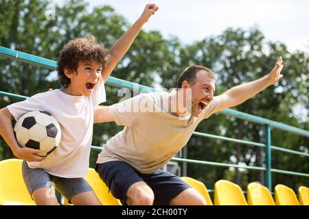 Uomini che guardano una partita di calcio allo stadio e che si acclamano Foto Stock