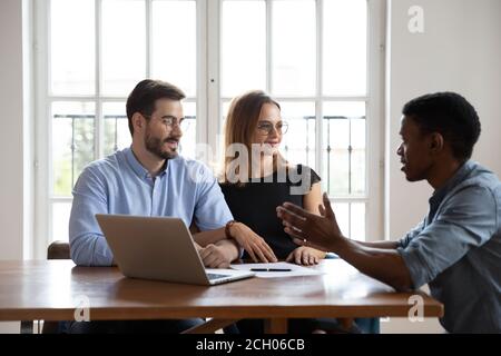 Riattore biraciale maschile consulta la coppia degli sposi novelli in ufficio Foto Stock