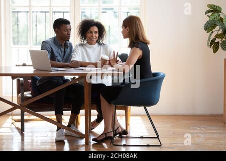 Giovane coppia biraciale consulenza parlando con la donna designer al meeting Foto Stock