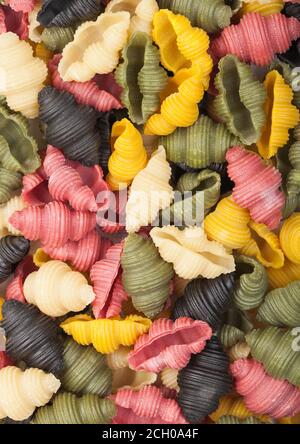 Conchiglioni crudi freschi tricolore pasta come fondo texture. Vista dall'alto Foto Stock