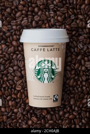LONDRA, Regno Unito - 09 SETTEMBRE 2020: Tazza di carta di caffè freddo Starbucks caffe latte sopra i chicchi di caffè crudo. Foto Stock
