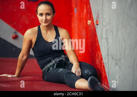 Ritratto colorato di attraente uoung climber donna che riposa dopo l'arrampicata esercizi sul tappetino in sala fitness Foto Stock