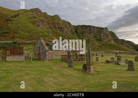 Luogo di sepoltura di Ecclesgreig ai piedi delle drammatiche scogliere della Riserva Naturale Nazionale di San Ciro, con le sue antiche tombe, la chiesa in rovina e Watc Foto Stock