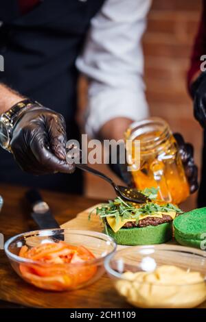 Lo Chef rendendo hamburger di manzo all'aperto sulla cucina aperta International Food festival evento. Cucina di strada pronti a servire su un cibo in stallo. Foto Stock