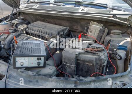 controllo della tensione della batteria dell'auto sotto il cofano aperto della vettura. Concetto di controllo automobilistico. Stile di vita Foto Stock