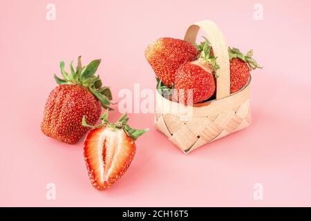 Fragole fresche nel cesto, frutta sul tavolo del mercato agricolo. Fragole rosse fresche, impilate in alto e riempite un piccolo cesto di tessuto su una parte posteriore rosa Foto Stock