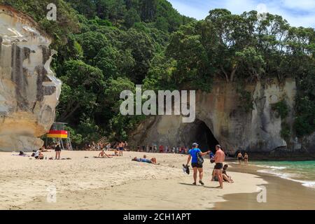 Cathedral Cove, Nuova Zelanda. Una folla di turisti sulla spiaggia di fronte al famoso arco di roccia naturale Foto Stock