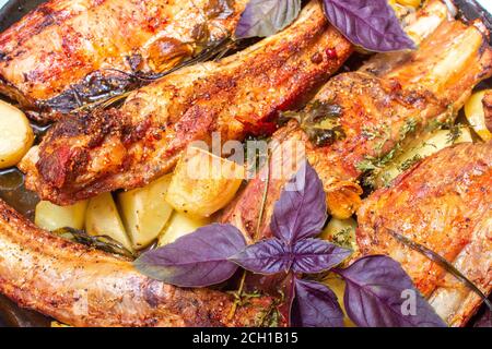 Ottimo piatto di costolette di maiale al forno con patate ed erbe su un tavolo di legno. Costolette di maiale alla griglia con spezie e patate al forno. Primo piano Foto Stock