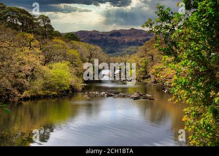 Ponte sovrastato su un fiume nel Parco Nazionale di Killarney, Irlanda. Ponte antico con un cielo drammatico Foto Stock