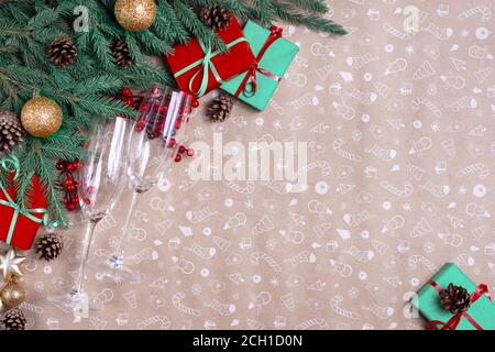 Decorazione di Natale su uno sfondo di carta d'arte. Rami di abete natalizio, scatole regalo con nastro rosso, decorazione rossa, scintille e bicchieri di champagne. Xmas An Foto Stock