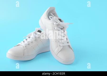 Paio di nuove sneaker bianche su sfondo blu. Nuove scarpe sportive in pelle bianca. Scarpe sportive per running, tennis, jogging. CopySpace Foto Stock