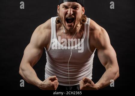 l'uomo arrabbiato con la bocca aperta sta tensionando i suoi muscoli Foto Stock