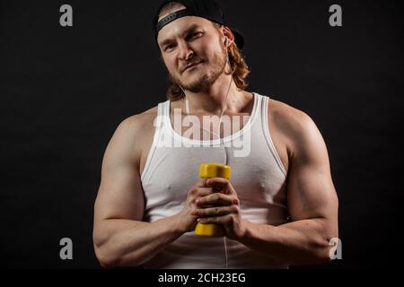 un sportivo con i capelli giusti, innocuo, che tiene in mano il leggero manubri giallo Foto Stock