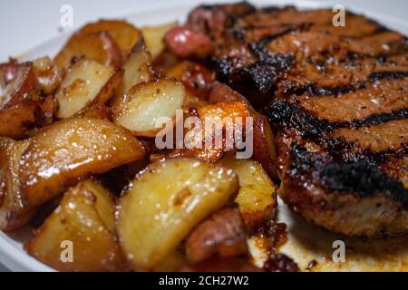 Un primo piano di Juicy Steak e patate su Uno sfondo bianco puro Foto Stock