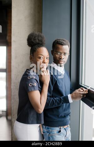 Gli studenti africani premurosi stanno in piedi vicino alla finestra panoramica Foto Stock