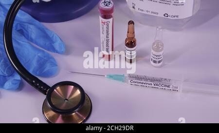 Vaccino per il concetto pandemico del coronavirus. COVID-19 attributi: Analisi del sangue, vaccino, iniezione, occhiali di protezione e guanti blu. Foto Stock