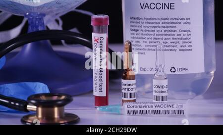 Vaccino per il concetto pandemico del coronavirus. COVID-19 attributi: Analisi del sangue, vaccino, iniezione, occhiali di protezione e guanti blu. Foto Stock