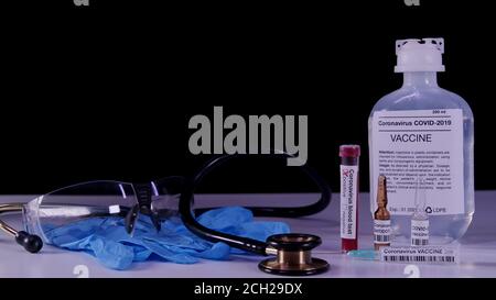 Vaccino per il concetto pandemico del coronavirus. COVID-19 attributi: Analisi del sangue, vaccino, iniezione, occhiali di protezione e guanti blu. Foto Stock