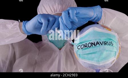 Concetto di vaccino coronavirus COVID-2019. Uomo in uniforme bianca di sicurezza e maschera facendo l'iniezione ad un mondo infettato con coronavirus. Cura per pandemia, Foto Stock