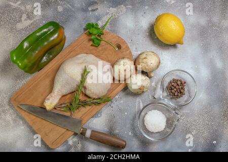 Cosce di pollo crude con limone fresco, funghi e rosmarino e spezie su fondo di legno nero. Vista dall'alto. Spazio libero per il testo. Foto Stock