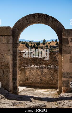 Interno della chiesa romanica Ermita de San Frutos. Eremo abbandonato costruito sulla cima di una collina tra le scogliere. Arco rotondo ancora in piedi fatto di pietra. Foto Stock