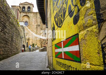 Pasajes, Gipuzkoa, Paesi Baschi, Spagna - 17 Luglio 2019 : Murale con bandiera ikurrina e chiesa di San Giovanni Battista in background. Foto Stock