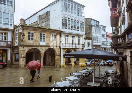 Betanzos, provincia di Coruna, Galizia, Spagna - 11 Febbraio 2020 : la gente cammina sulla piazza principale della città vecchia in una giornata di pioggia. Foto Stock