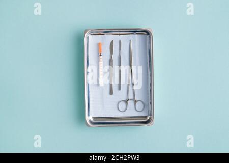 Flatlay della ciotola medica con strumenti chirurgici e siringa con iniezione Foto Stock