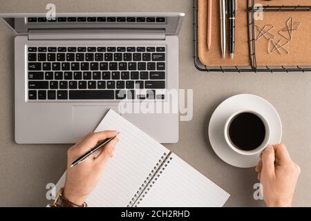 Vista dall'alto delle mani di un giovane uomo d'affari con una tazza di note di lavoro per la preparazione del caffè Foto Stock
