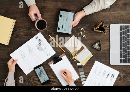 Panoramica delle mani di giovani stilisti che discutono di nuova moda raccolta Foto Stock