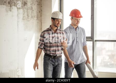 due allegri architetti sorridenti che camminano nell'area dell'edificio Foto Stock