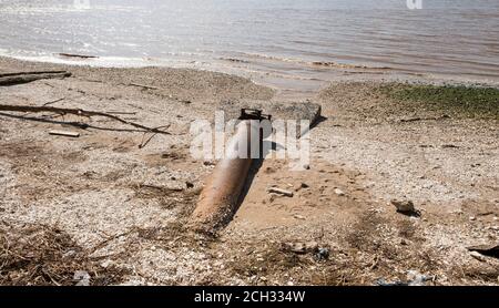 Tubo di ferro arrugginito esposto su una riva del fiume Foto Stock