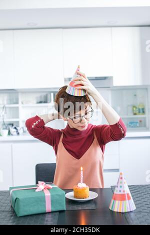 giovane animatrice femminile che mette il cappello da festa sulla sua testa. preparatevi per il compleanno. Foto Stock