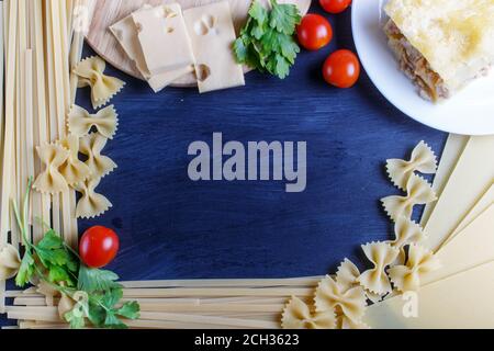 Cornice con pasta italiana ingredienti su fondo di legno nero. Copia spazio, vista dall'alto. Foto Stock