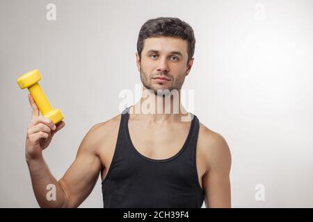 uomo serio che tiene in mano gli attrezzi sportivi Foto Stock