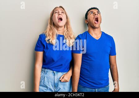 Giovane coppia interrazziale che indossa abiti casual arrabbiato e pazzo urlando frustrato e furioso, gridando con rabbia. Rabbia e concetto aggressivo. Foto Stock