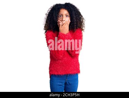 African american bambino con capelli ricci indossando casual inverno pullover scioccato bocca di copertura con le mani per errore. Concetto segreto. Foto Stock