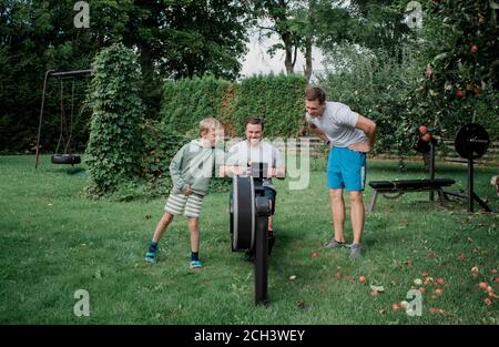 due uomini e il loro figlio che lavorano a casa loro palestra in giardino Foto Stock