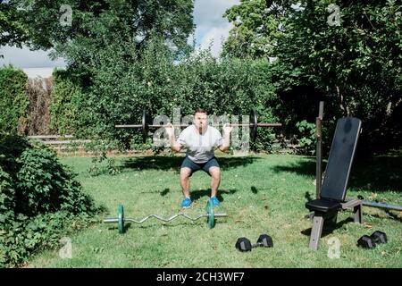 uomo che lavora a casa in giardino con il suo attrezzature da palestra Foto Stock