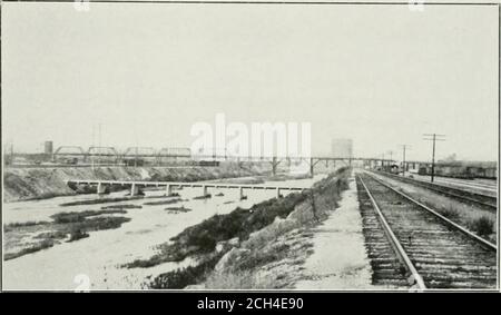 . Relazione sull'eliminazione del passaggio ferroviario e terminal passeggeri e merci a Los Angeles. nta Fe y.ards sul Iiglit e trespolo approachross .Salt Lake yard sulla sinistra. Il carattere del letto del fiume è anche ben mostrato, anche se c'era una quantità insolitamente grande di acqua nel fiume. Il pesante rapimento delle banche è necessario per prevenire l'erosione in tempi di Hood. Quarto Ponte di strada a Fourth Street ci sono due strutture composite ciascuna di circa 2.100piedi di lunghezza, uno che porta la strada e l'altro la ferrovia di Los Angeles presente e PRniosF.n P.KincES su Los Angei.es Ri Foto Stock