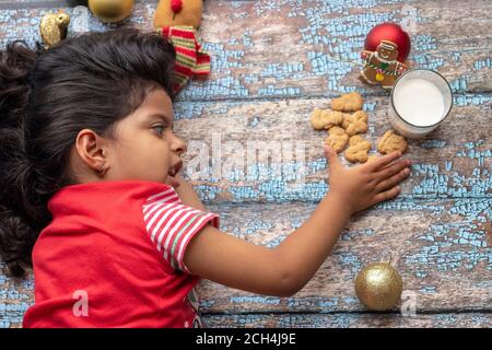 Carino bambina sta giocando con Santa's biscotti e latte a Natale Foto Stock