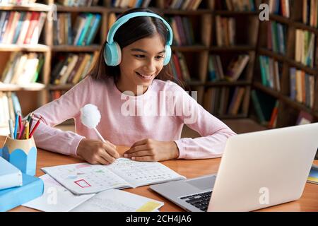 Felice scuola indiana ragazza imparare classe online su video zoom chiamata su laptop. Foto Stock
