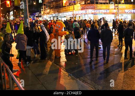 Halloween notte carnevale . Chiesa strada, persone che camminano in maschere e costumi diversi. Foto Stock