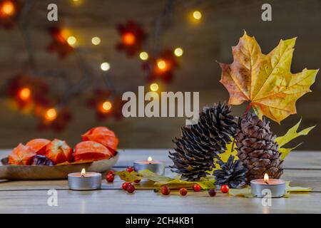 Composizione autunnale con coni, fisalis, foglie d'acero e candele Foto Stock