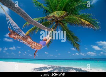 Donna in amaca sotto il palm tree in Maldive Foto Stock