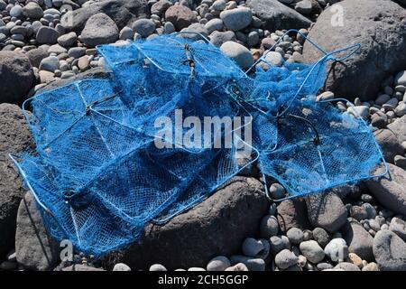 Reti blu danneggiate sulla costa rocciosa grigia Foto Stock
