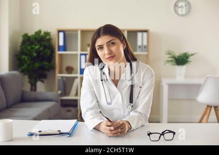 Dottore femminile che dà la consultazione in linea al paziente guardando la webcam. Foto Stock