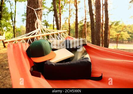 Amaca con borsa, cappello e libro in foresta il giorno d'estate Foto Stock