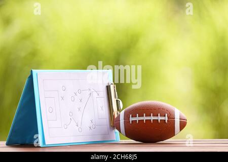 Palla di rugby con schema di gioco di calcio sul tavolo all'aperto Foto Stock